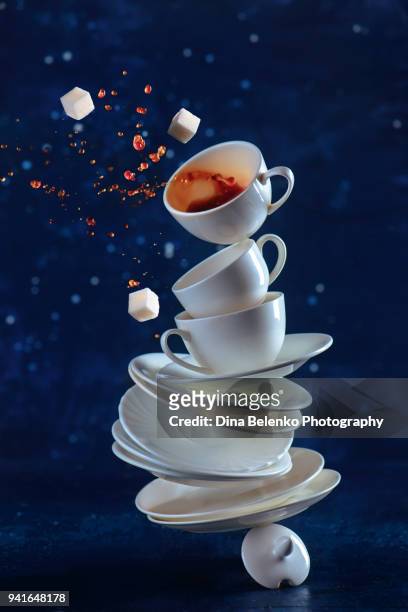 stack of white porcelain coffee cups balancing on a table. dynamic drink photography with coffee splash on a dark background. - sugary coffee drink stock pictures, royalty-free photos & images