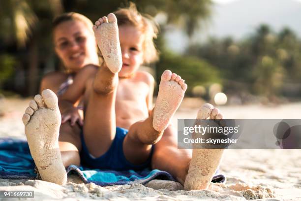 sandy voeten van een moeder en zoon op het strand. - voetzool stockfoto's en -beelden