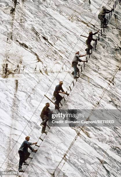 Quarrymen climbing up a ladder at a marble quarry in Carrara, Italy.