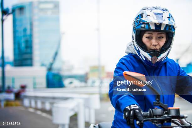 a woman who stops the bike and looks somewhere. - crash helmet stock pictures, royalty-free photos & images