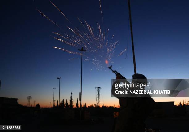 Turkish-backed rebel fighter fires ammunition as buses arrive at the Abu al-Zindeen checkpoint near the northern Syrian town of al-Bab transporting...