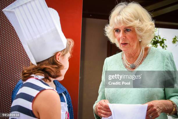 Camilla, Duchess of Cornwall talks with Elizabeth Ross-9 and Max Bishop-12 as they help prepare lamingtons during an official visit to the Lady...