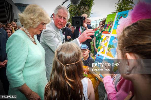 Prince Charles, Prince of Wales adds his finishing touch to a children's painting with Camilla, Duchess of Cornwall during their official visit to...