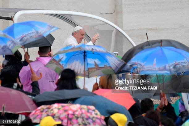 Pope Francis greets the crowd standing in the rain as he arrives for a weekly general audience at St Peter's square on April 4, 2018 in Vatican. /...