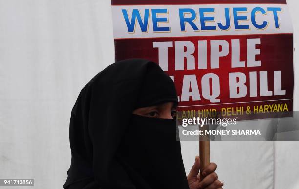 An Indian Muslim woman holds a placard during a protest against the "triple talaq bill" in New Delhi on April 4, 2018. Muslim women in India have...