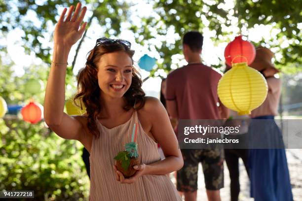 zomer tuinfeest. mooie vrouw zwaaien naar een vriend - summer cocktails garden party drinks stockfoto's en -beelden