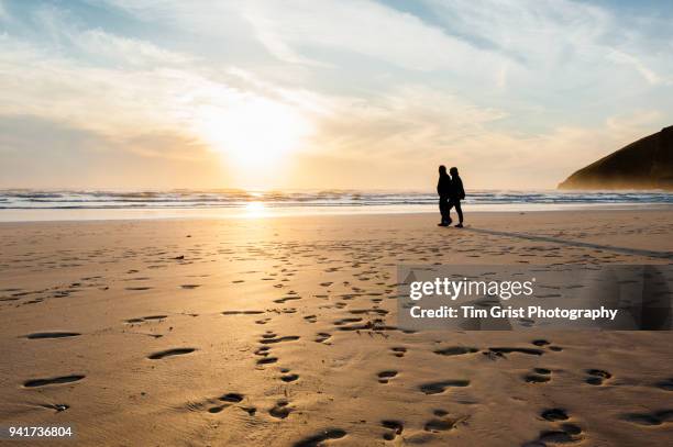 silhouette of a couple on a beach at sunset - mawgan porth fotografías e imágenes de stock