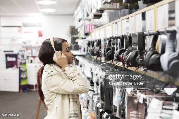 young woman in shop looking at headphones - choice music group stock pictures, royalty-free photos & images