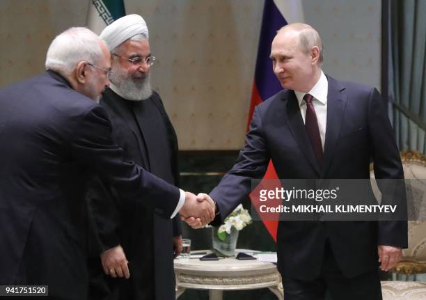 Russian President Vladimir Putin shakes hands with Iranian Foreign Minister Mohammad Javad Zarif during a meeting with Iranian President Hassan...