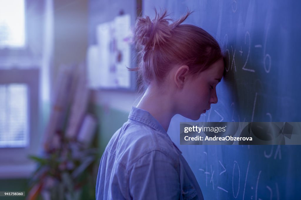 數學課上的那個十幾歲的女孩被數學公式淹沒了。壓力, 教育, 成功的概念。