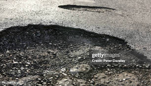 road with dangerous potholes - asfalt stockfoto's en -beelden