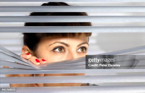 obsessive woman spying on her neighbour through window - suspicion stock pictures, royalty-free photos & images