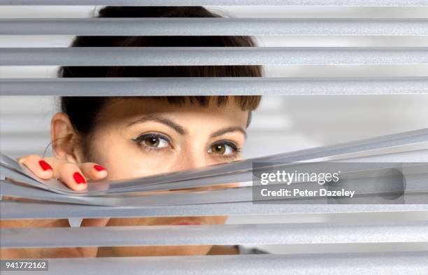 woman looking through window blinds - bad neighbor foto e immagini stock