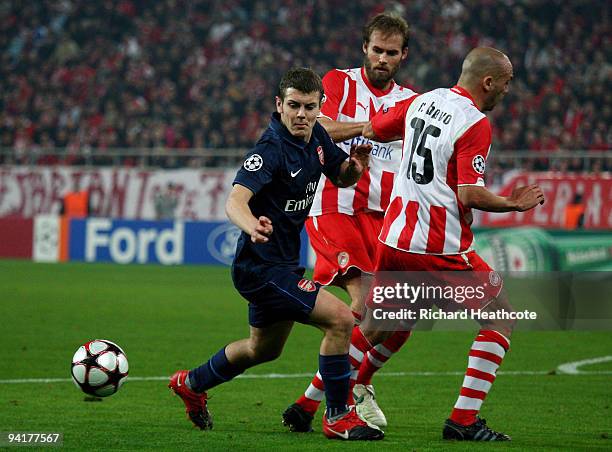 Jack Wilshere of Arsenal goes past Olof Mellberg and Raul Bravo of Olympiakos during the UEFA Champions League Group H match between Olympiakos and...