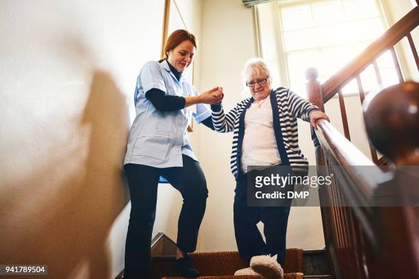 pflegeperson helfen senior frau treppen hinunter - care stock-fotos und bilder