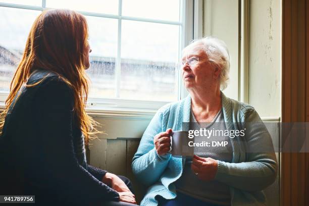 alte frau im gespräch mit ihrer kleinen tochter zu hause - old man young woman stock-fotos und bilder