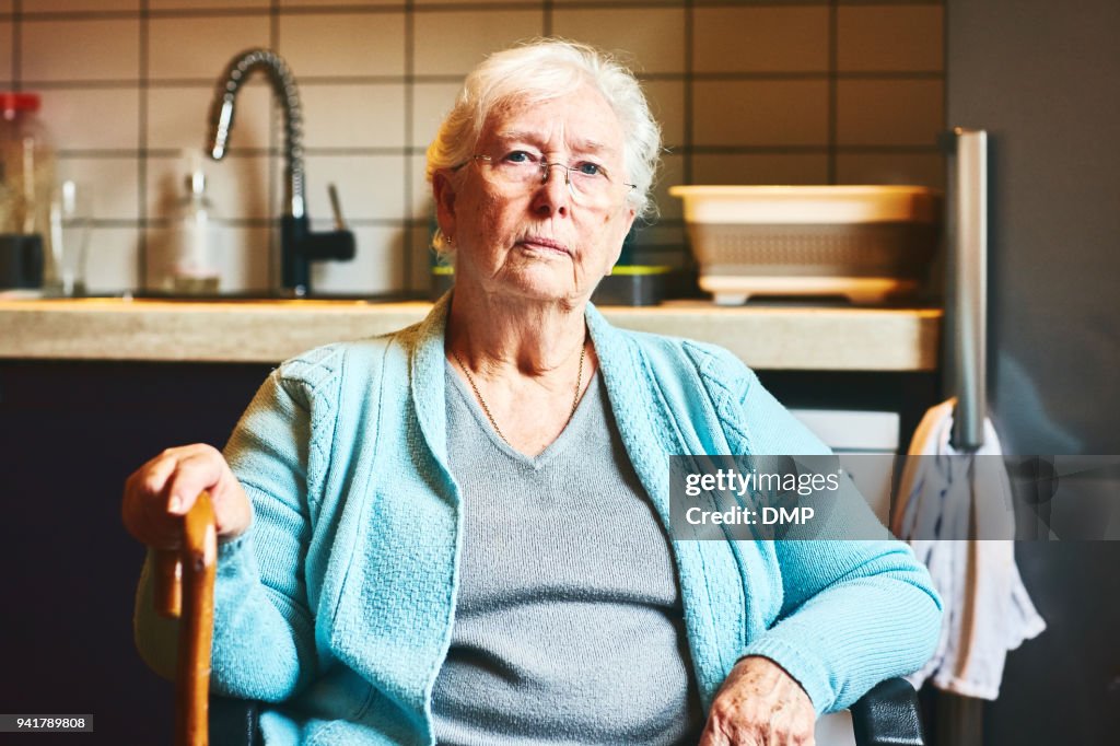 Ältere Frau sitzt in Küche