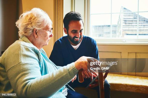 male nurse showing a digital tablet to an elderly woman - old point comfort stock pictures, royalty-free photos & images