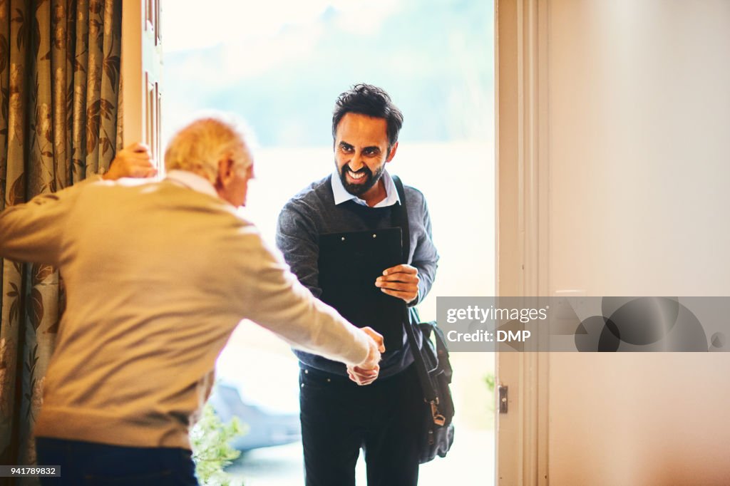 Senior man welcoming a healthcare worker - Home visit