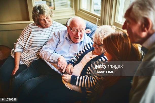 groep van ouderen met jonge vrouw met behulp van digitale tablet - hospitium stockfoto's en -beelden