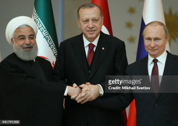 Russian President Vladimir Putin , Turkish President Recep Tayyip Erdogan and Iranian President Hassan Rouhani hold hands as they pose for a photo...