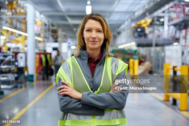 mature female engineer standing with arms crossed - factory engineer woman imagens e fotografias de stock