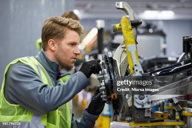 ingegnere maschile fiducioso che esamina il telaio dell'auto - manufacturing foto e immagini stock