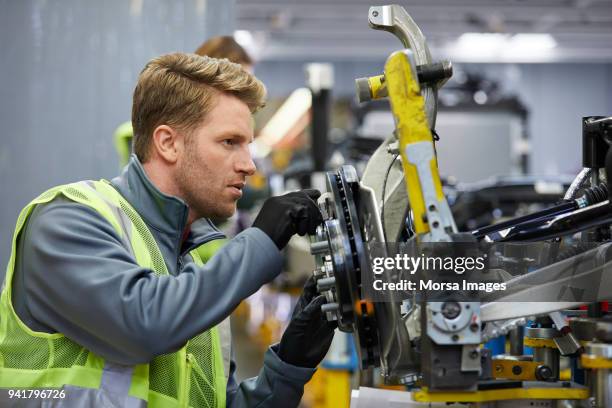 vertrouwen mannelijke ingenieur behandeling van auto-chassis - assemblagelijn stockfoto's en -beelden