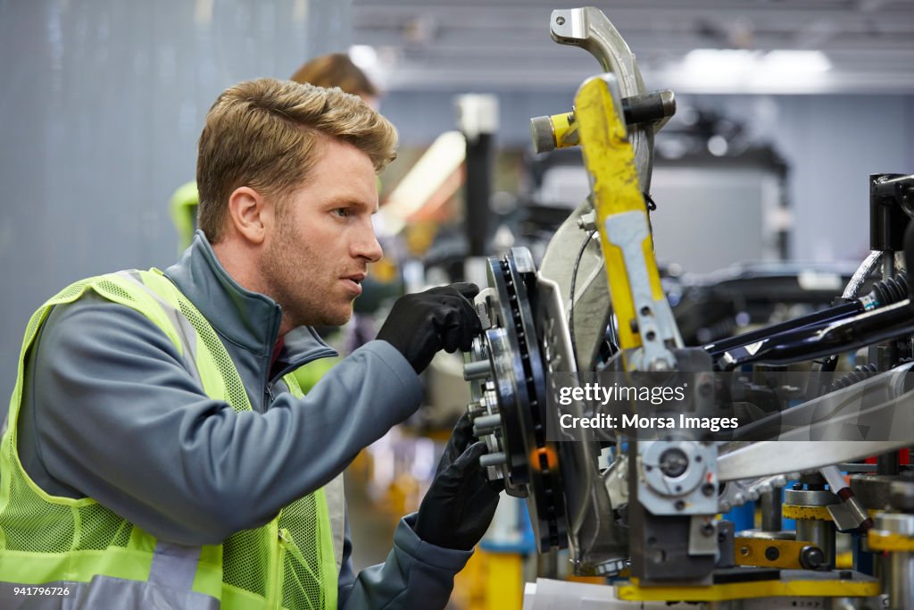 Confident male engineer examining car chassis