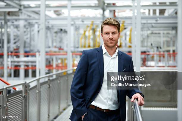 confident handsome businessman standing at factory - three quarter length stock pictures, royalty-free photos & images