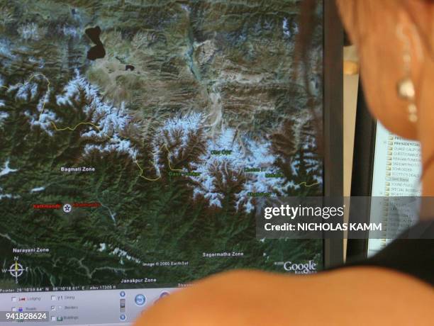 Woman looks at a view of the snow-covered Himalaya mountains on Google Earth in Washington 03 August 2005. The world at your fingertip, with the...