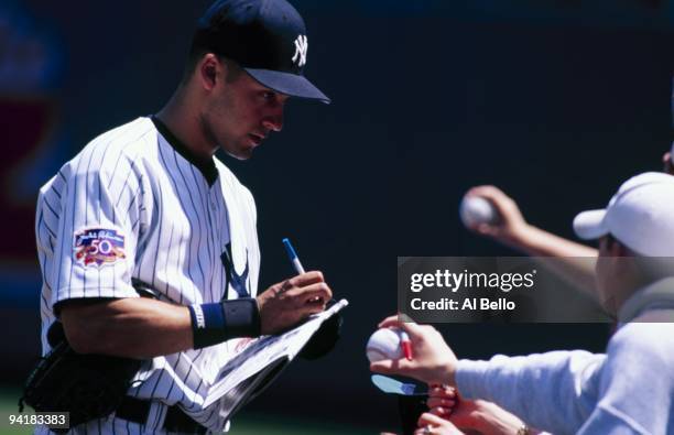 Derek Jeter of the New York Yankees signs autographs before the game against the Boston Red Sox at Yankee Stadium on May 24, 1997 in the Bronx, New...