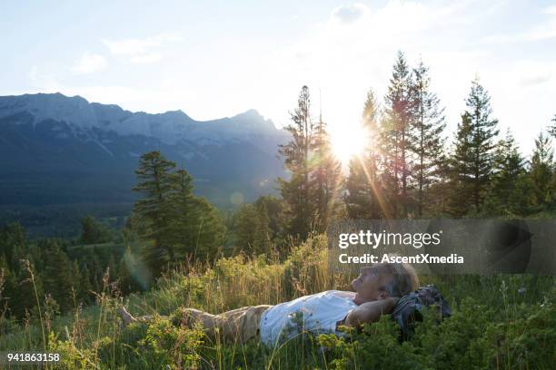 man ligt op terug in berg weide - lying down stockfoto's en -beelden