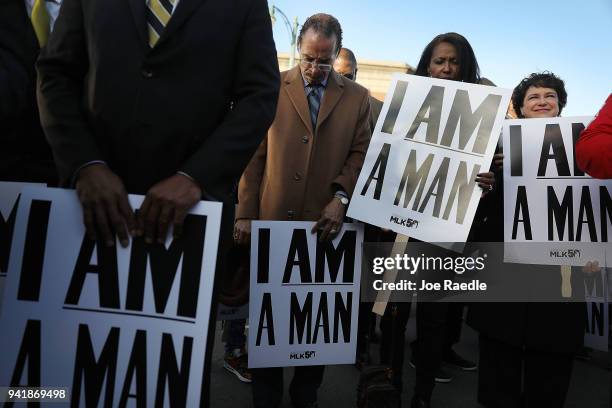 Pastor Kenneth Whalum holds 'I Am A Man' signs, in reference to the sanitation workers strike in 1968, as he bows his head in prayer during an event...