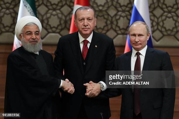 Iran's President Hassan Rouhani, Turkey's President Recep Tayyip Erdogan and Russia's President Vladimir Putin shake hands after a joint press...