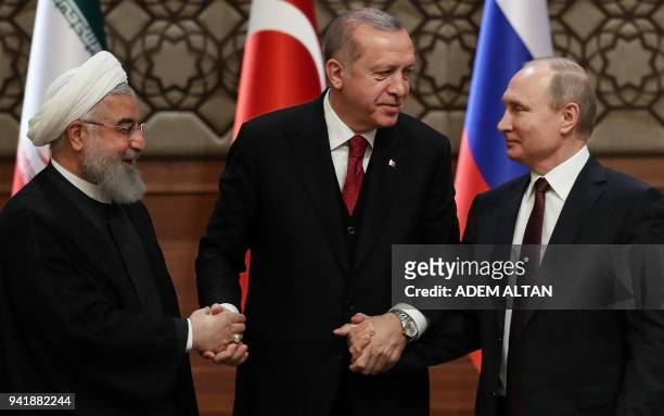 Iran's President Hassan Rouhani, Turkey's President Recep Tayyip Erdogan and Russia's President Vladimir Putin shake hands after a joint press...