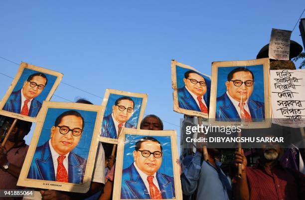 Indian activists holds portraits of 20th century Indian social reformer B. R. Ambedkar while shouting slogans during a protest against a Supreme...