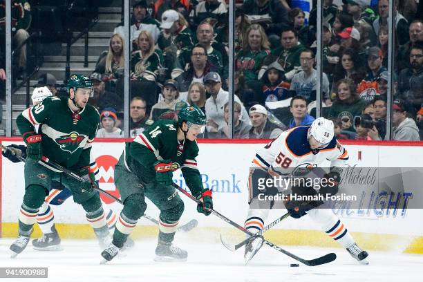 Joel Eriksson Ek of the Minnesota Wild takes the puck from Anton Slepyshev of the Edmonton Oilers as teammate Carson Soucy looks on during the game...