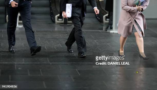 Business men and women walk in the City of London on April 4, 2018. - Employers with more than 250 staff have until midnight on Wednesday to publish...