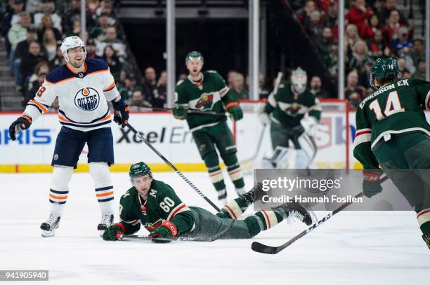 Carson Soucy of the Minnesota Wild passes the puck to teammate Joel Eriksson Ek after being tripped by Anton Slepyshev of the Edmonton Oilers during...