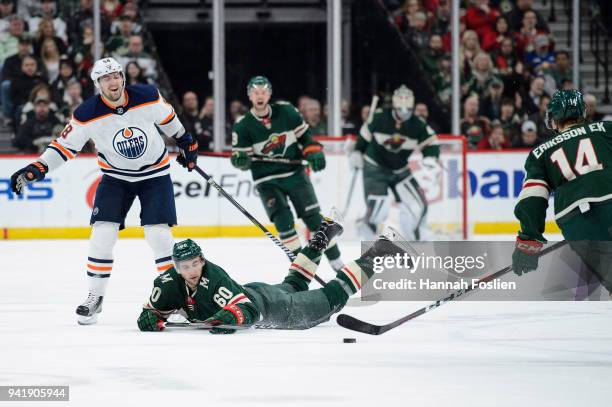 Carson Soucy of the Minnesota Wild passes the puck to teammate Joel Eriksson Ek after being tripped by Anton Slepyshev of the Edmonton Oilers during...