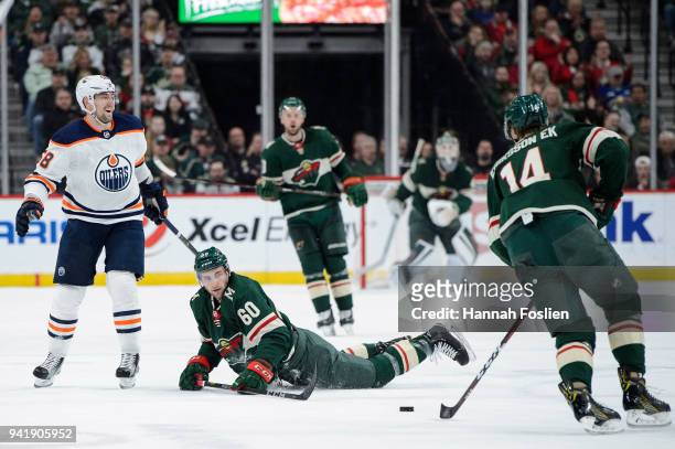 Carson Soucy of the Minnesota Wild passes the puck to teammate Joel Eriksson Ek after being tripped by Anton Slepyshev of the Edmonton Oilers during...