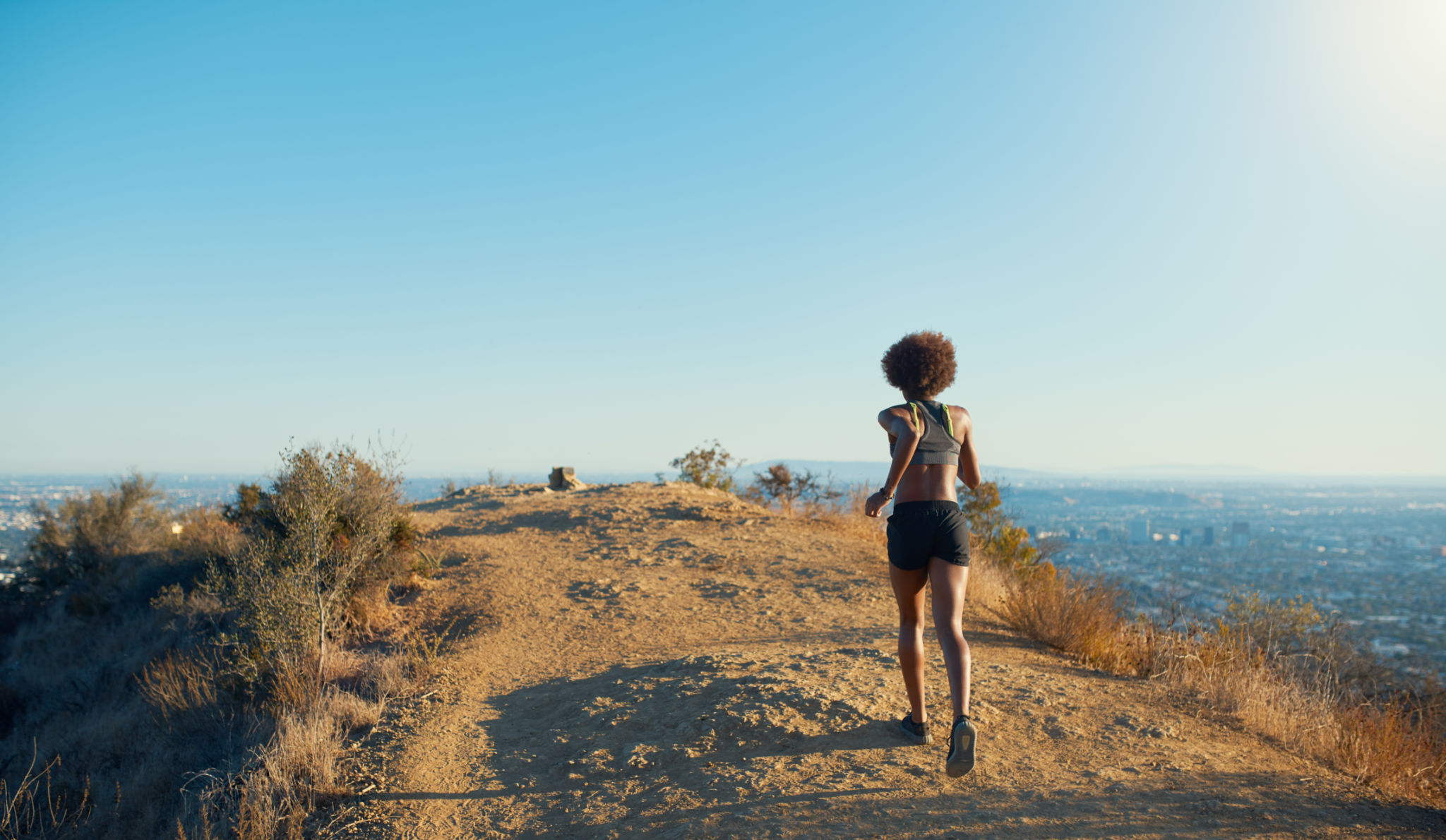 fit african american woman running at runyon canyon with los angeles in background fit african american woman running at runyon canyon with los angeles in background