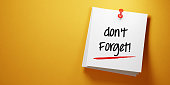 White Sticky Note With Don't Forget Message And Red Push Pin On Yellow Background