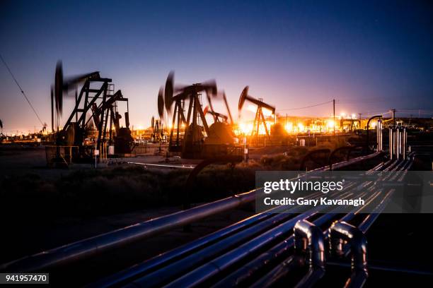 olie pupjacks whiring bij nacht - oil field stockfoto's en -beelden