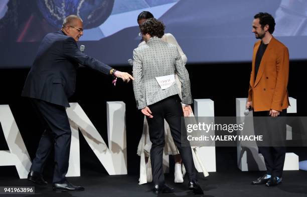 French journalist Laurent Weil shows British actor Alexander Vlahos his seat name tag that remained attached to his jacket, as he arrives on stage...