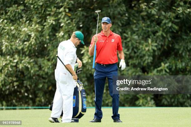 Matt Kuchar of the United States takes a club from his caddie John Wood on the eighth hole during a practice round prior to the start of the 2018...