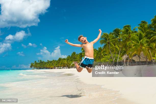 快樂男孩跳躍在加勒比海島的海灘 - kemter 個照片及圖片檔