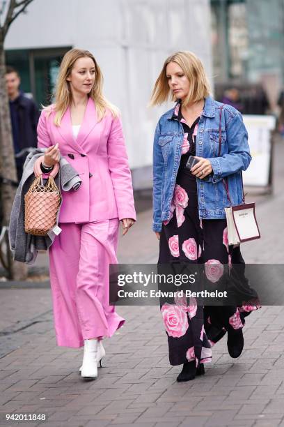 Guest wears a pink blazer jacket, a bag, pink flare pants, white shoes ; a guest wears a blue denim jacket, a dress with floral prints during London...