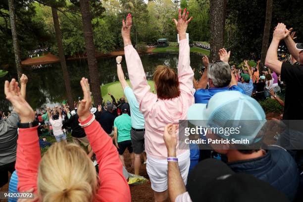 Patrons cheer on the ninth hole after Gary Nicklaus, Jr. Hit a hole-in-one during the Par 3 Contest prior to the start of the 2018 Masters Tournament...